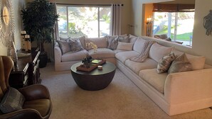 A spacious living room with a large sectional sofa, a coffee table, and a potted plant.