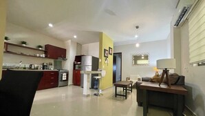 Eine moderne Küche mit Edelstahlgeräten, ein Essbereich mit Tisch und Stühlen sowie ein Wohnzimmer mit Sofa und Lampe.