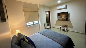 Ein Schlafzimmer mit einem Bett, einem Sessel, einem Schreibtisch und einem Fernseher.