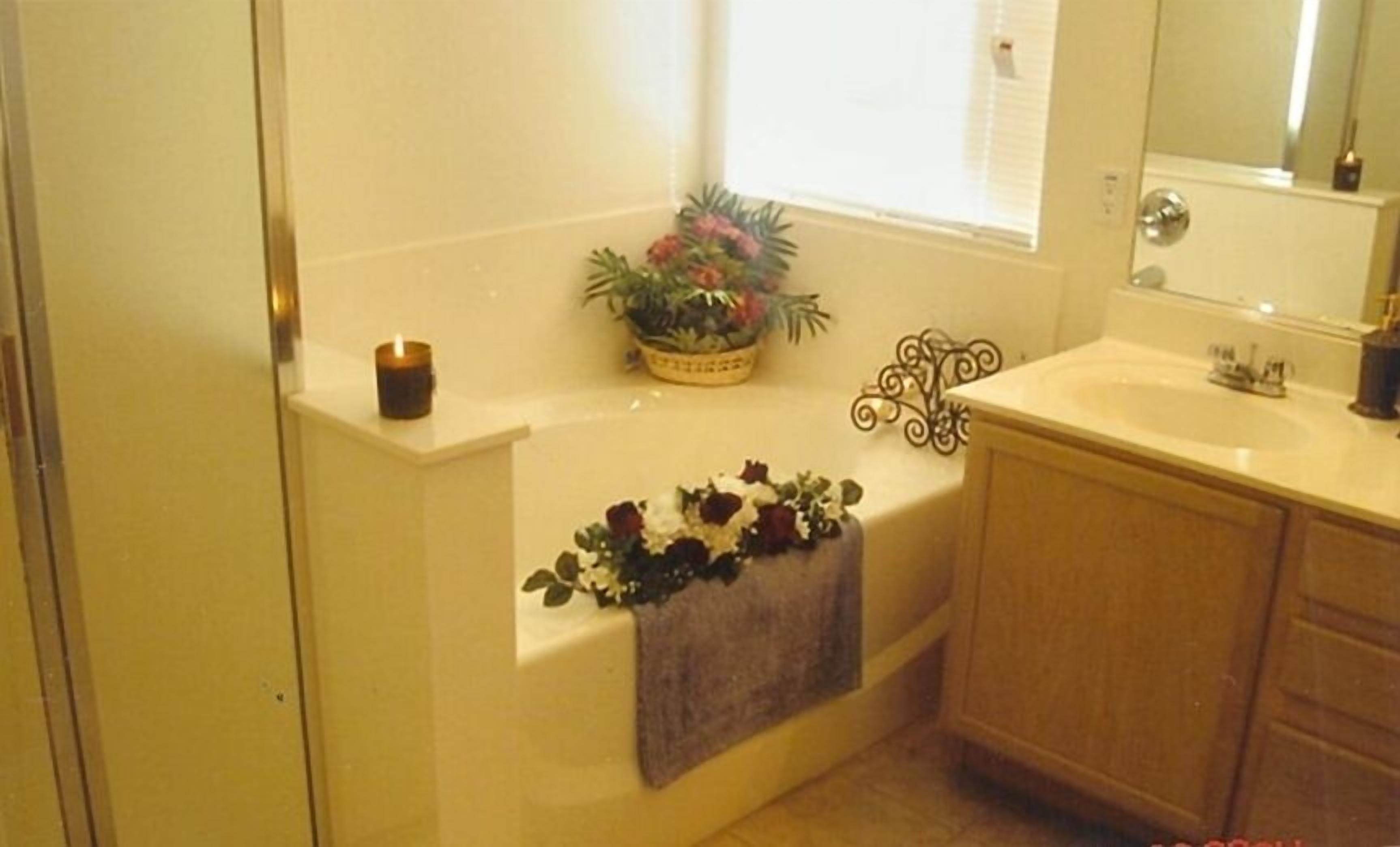 A bathroom with a bathtub, a window, a sink, and a mirror.