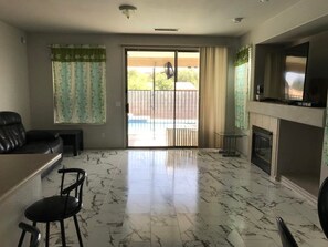 Un vaste salon doté d’une grande porte-fenêtre coulissante donnant sur un balcon, d’une cheminée et d’un téléviseur fixé au mur.