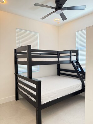 Ein Etagenbett mit Deckenventilator und Fenstern mit Jalousien.