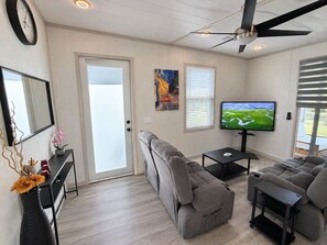A modern living room with a sofa, a coffee table, a TV, and a ceiling fan.