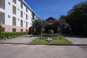 Pátio de hotel com um jardim central, um vaso grande e um edifício com várias varandas.