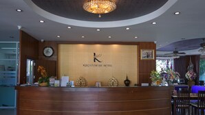A reception desk with a logo, a clock, and decorative items. - Kirimathani Hotel (Mueang Loei)