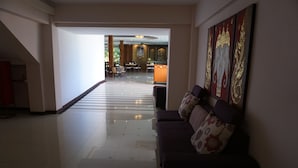 A hotel lobby with a reception desk, seating area, and a staircase leading to another floor. - Kirimathani Hotel (Mueang Loei)