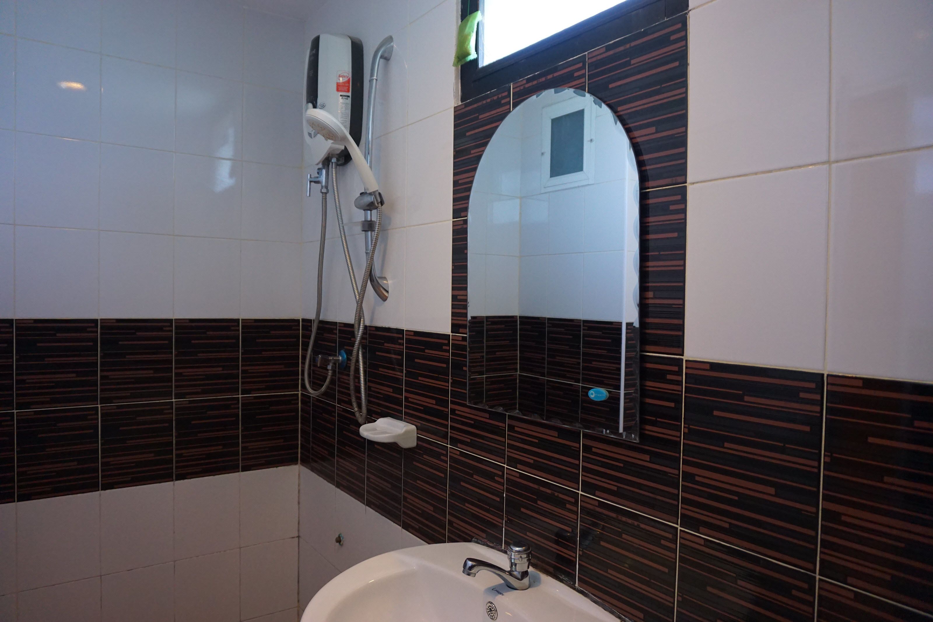 A bathroom with a white sink, a handheld showerhead, a towel rack, and a mirror with a small window.