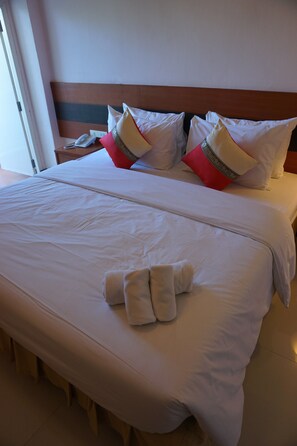 Ein Hotelzimmer mit einem großen Bett, weißer Bettwäsche und einem Holzkopfstück.