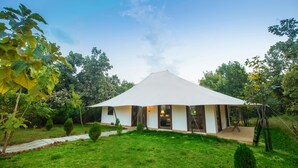 A modern, white tent-style building with a flat roof, surrounded by a well-maintained grassy area and trees. - Tuli Veer Bagh Resort (Ramtek)