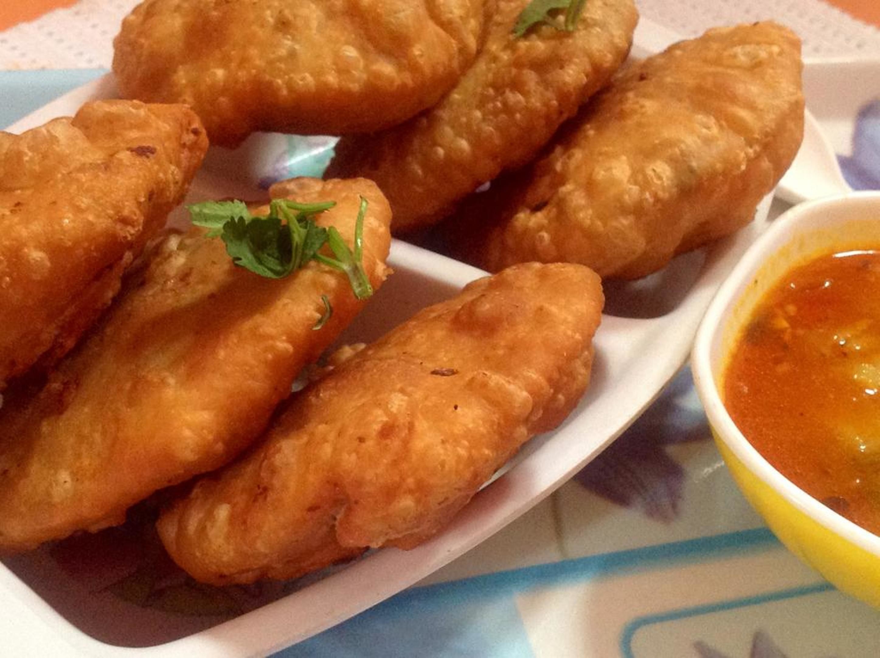 A plate of fried items garnished with parsley, accompanied by a bowl of dipping sauce.