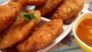 A plate of fried items garnished with parsley, accompanied by a bowl of dipping sauce.