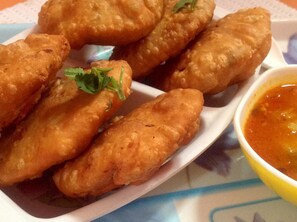 Une assiette de mets frits, garnie de persil, accompagnée d’un bol de sauce pour tremper.
