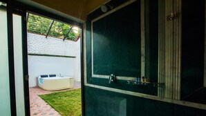 A bathroom with a large mirror, a bathtub, and a shower area. - Tuli Veer Bagh Resort (Ramtek)