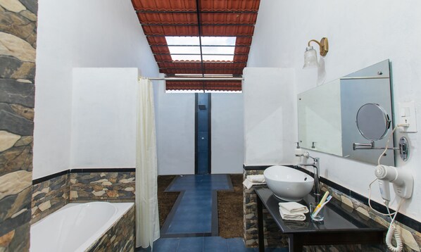 A bathroom with a stone wall, a white sink, a mirror, a shower curtain, and a ceiling fan.