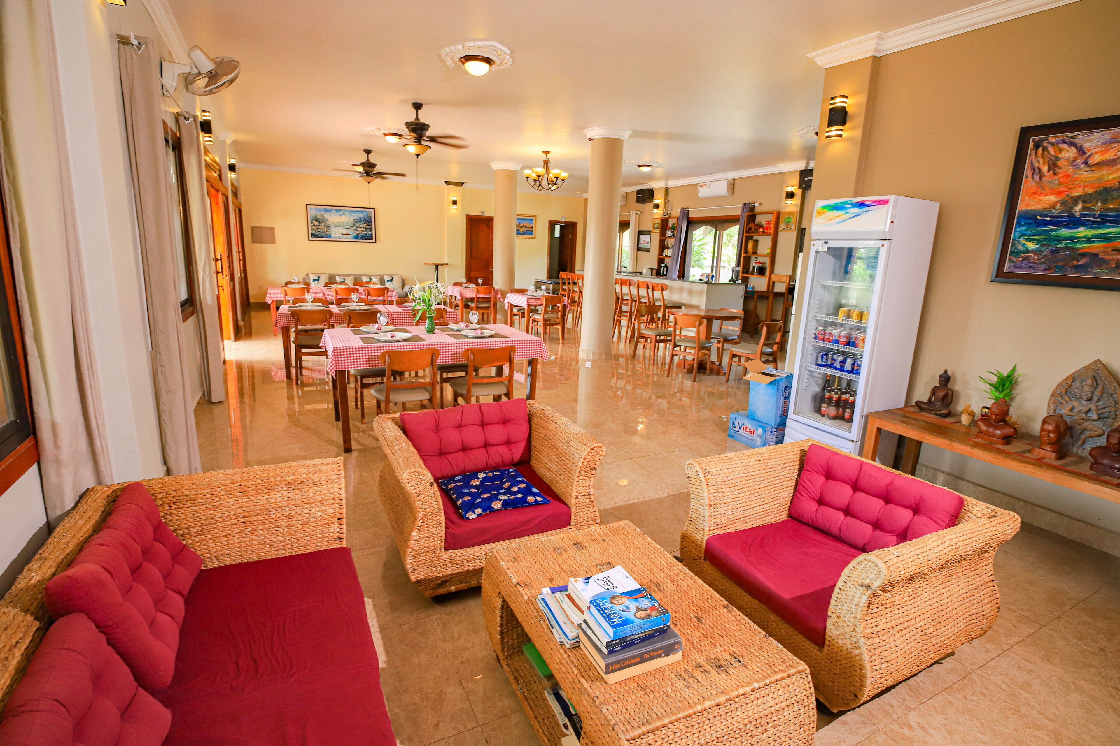 A spacious lobby with wicker furniture, a dining area, and a refrigerator stocked with beverages.