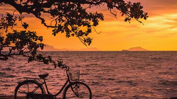 Una bicicleta estacionada junto al mar con un atardecer de fondo.