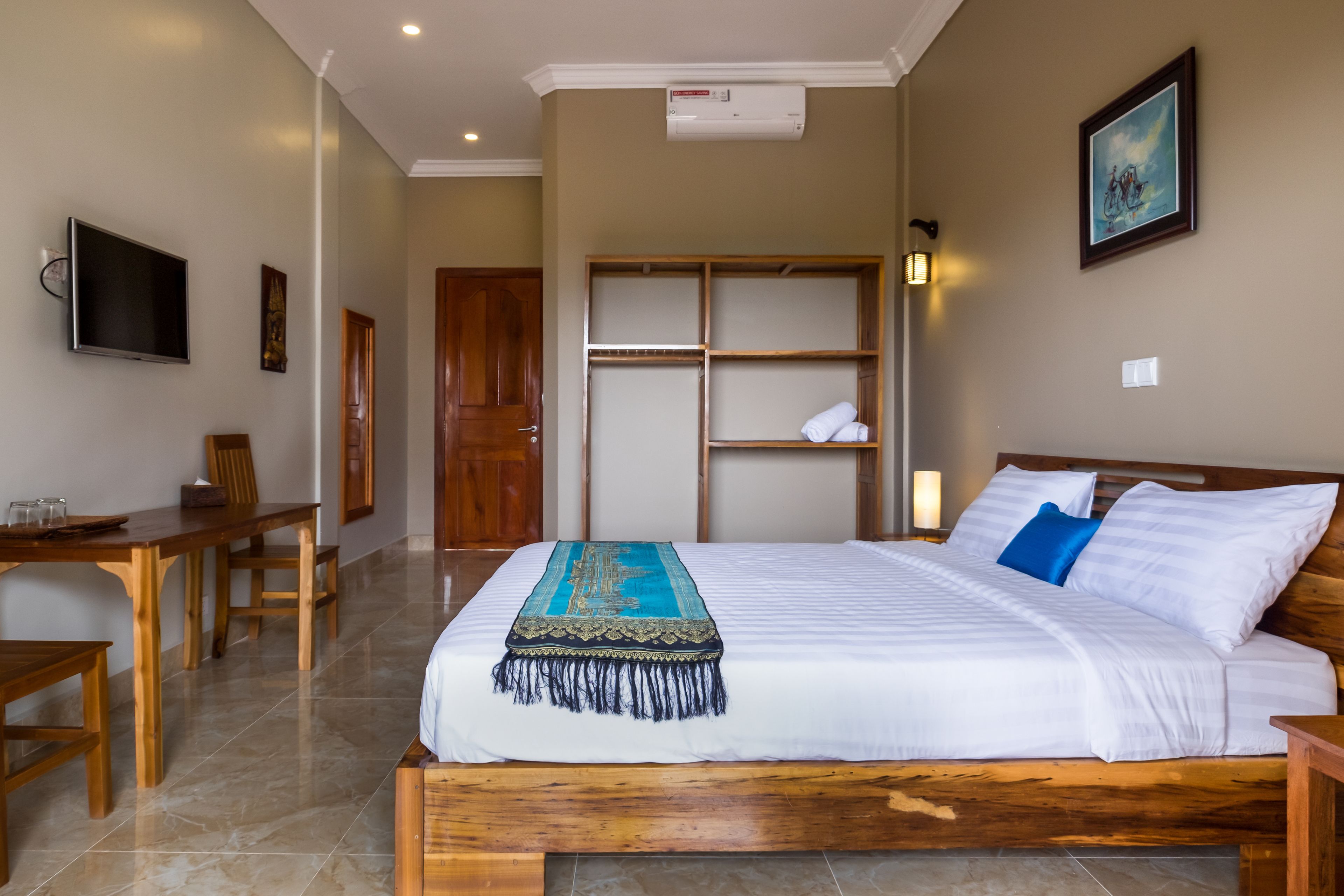 Una habitación de hotel con una cama de madera, televisión, escritorio y armario.