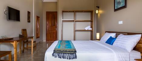 Una habitación de hotel con una cama de madera, televisión, escritorio y armario.