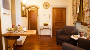Un salon chaleureux avec un plancher en bois, un canapé, une petite table sur laquelle est posé un vase, et une porte ornée d’une guirlande décorative.