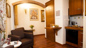 Un espace de vie compact comprenant un canapé, une petite table à manger, un coin cuisine avec un lave-vaisselle et un miroir décoratif.