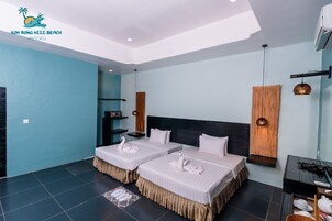 Habitación de hotel con dos camas, cabecero de madera, una mesita y un estante en la pared.