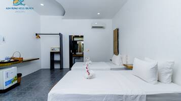 Habitación de hotel con dos camas, un escritorio pequeño, un refrigerador y aire acondicionado instalado en la pared.