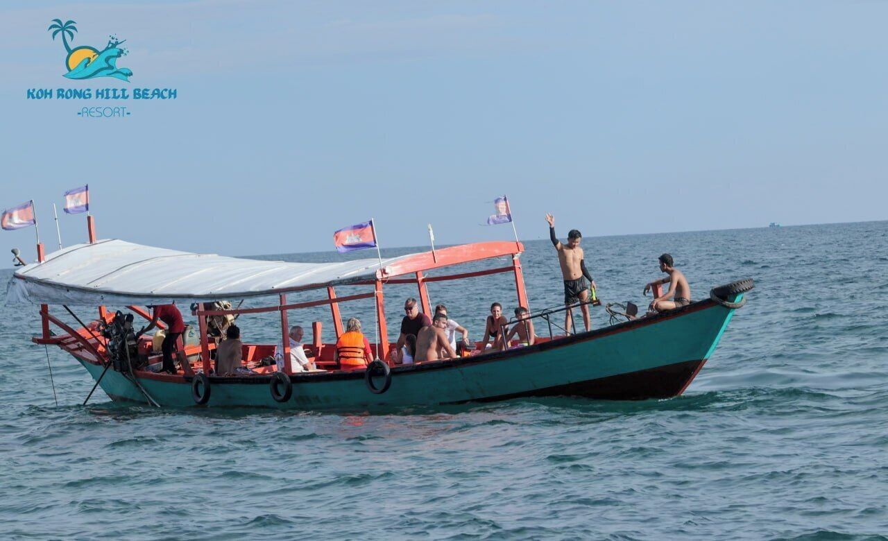 A boat with a covered deck and passengers, floating on calm water.