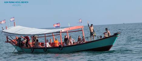 A boat with a covered deck and passengers, floating on calm water.