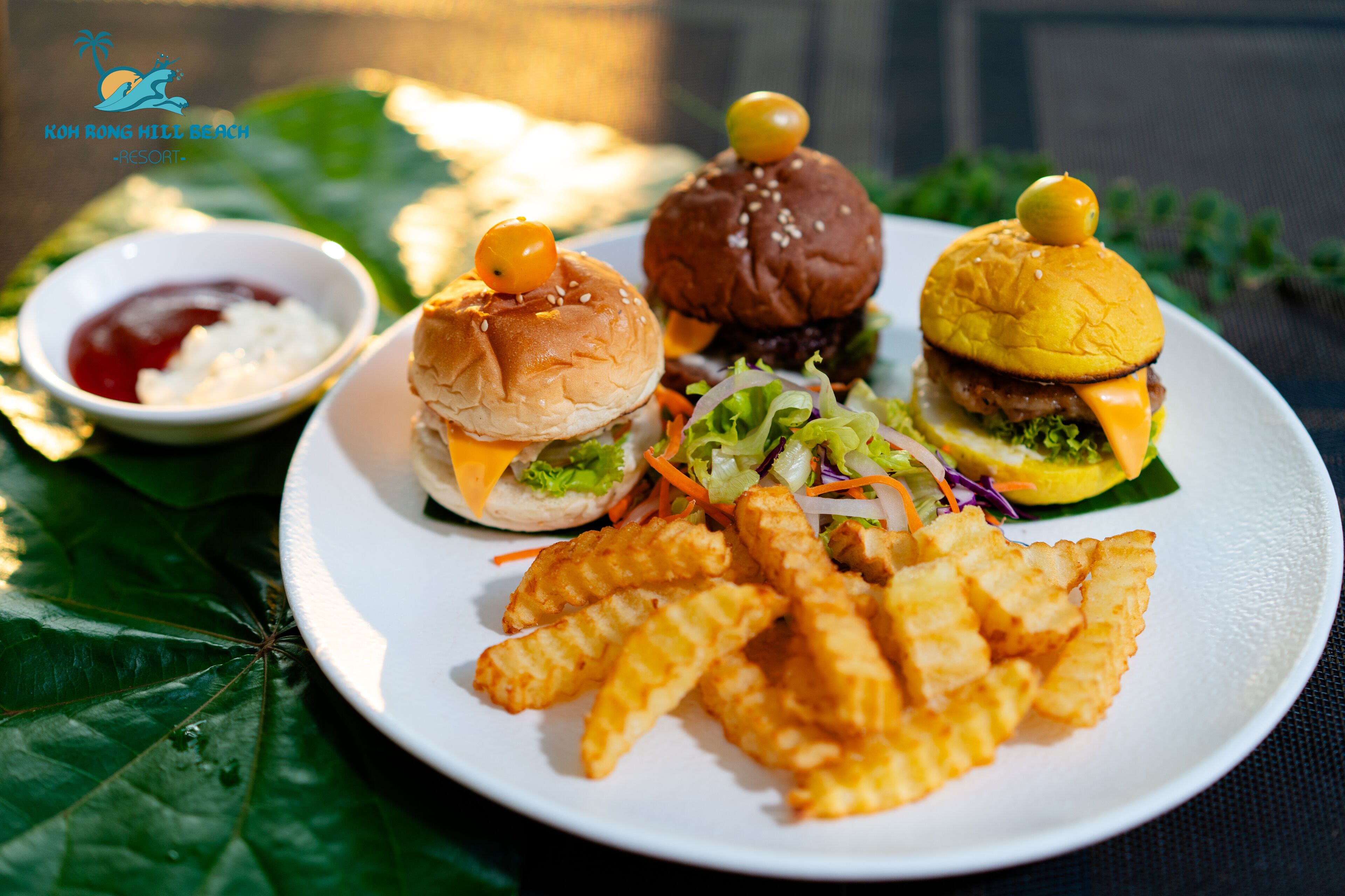 Un plato con tres hamburguesas, papas fritas y dos salsas para mojar.