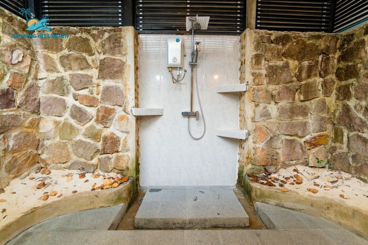 Un espace de douche aux murs en pierre, doté d’un banc intégré et d’une petite marche menant à celui-ci.