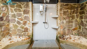 A stone-walled shower area with a built-in bench and a small step leading up to it.