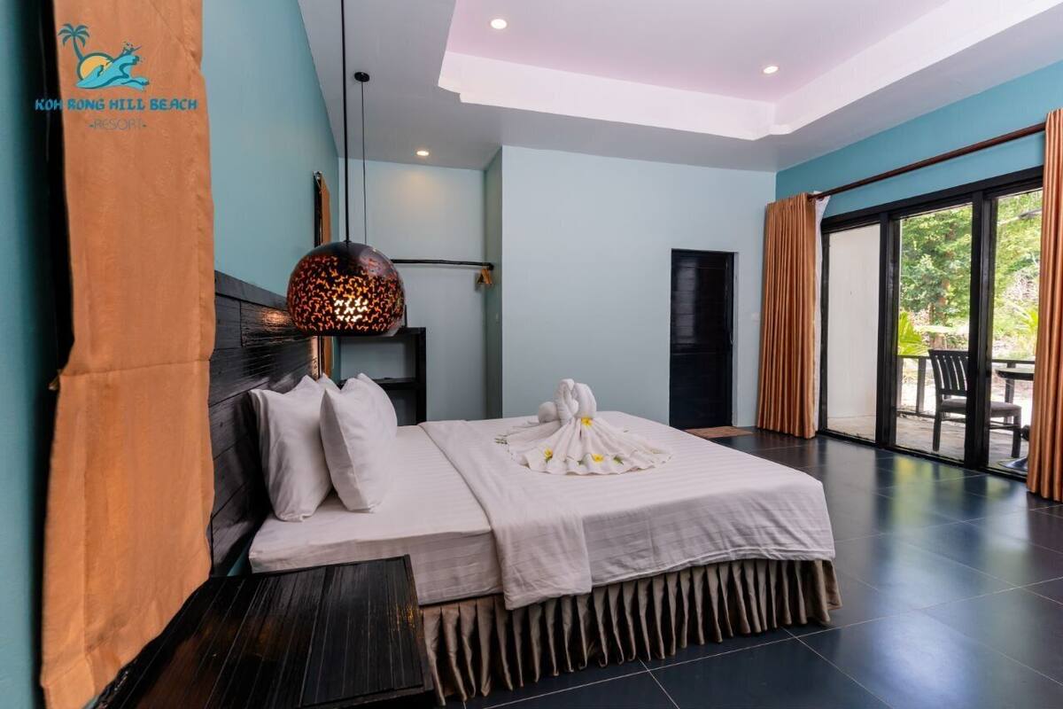 Una habitación de hotel moderna con una cama grande, una lámpara esférica original y vistas al exterior.
