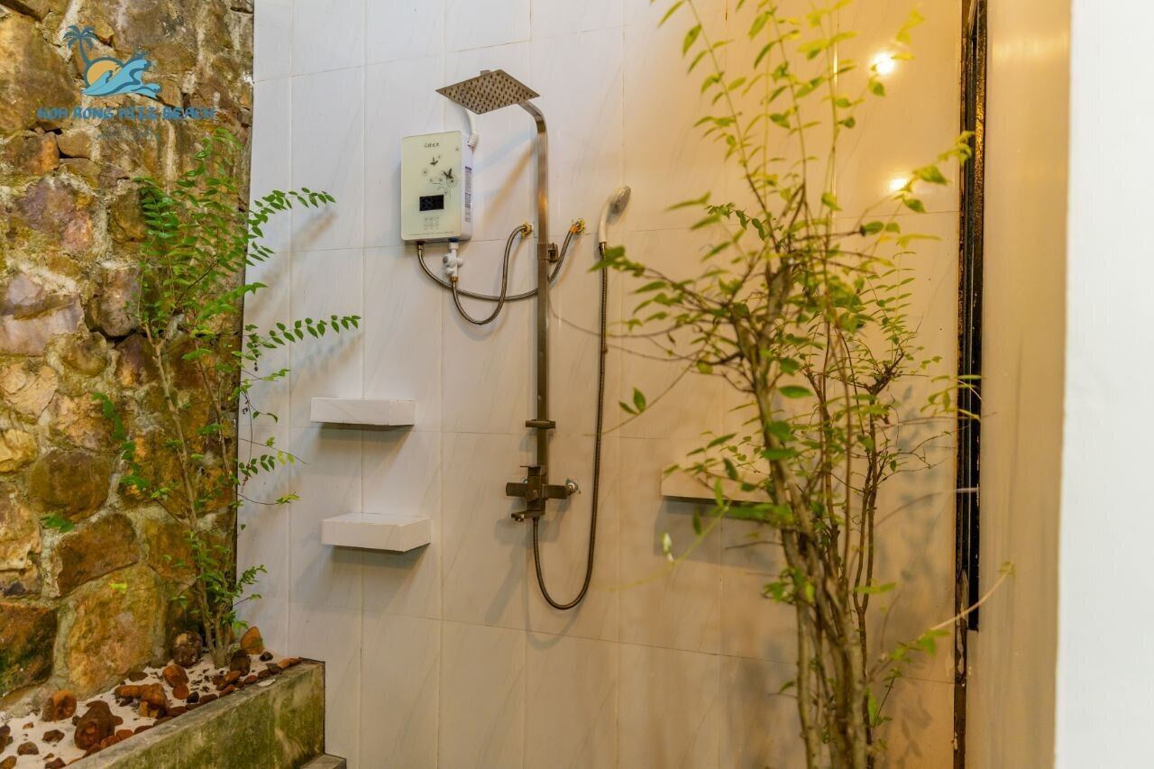 Un espacio de ducha con pared de piedra, un panel de control y una planta de bambú.