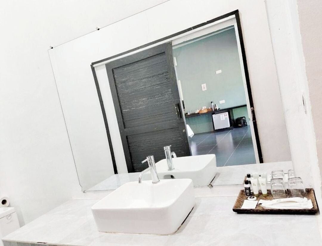 A modern bathroom with two white sinks, a large mirror, and a tray with toiletries.