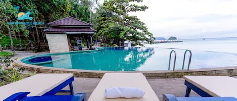 A pool area with lounge chairs and a small pavilion.