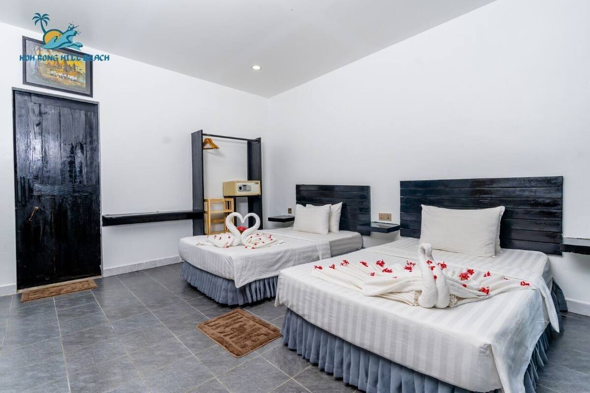 Habitación de hotel con dos camas, un armario, un espejo y un cuadro en la pared.