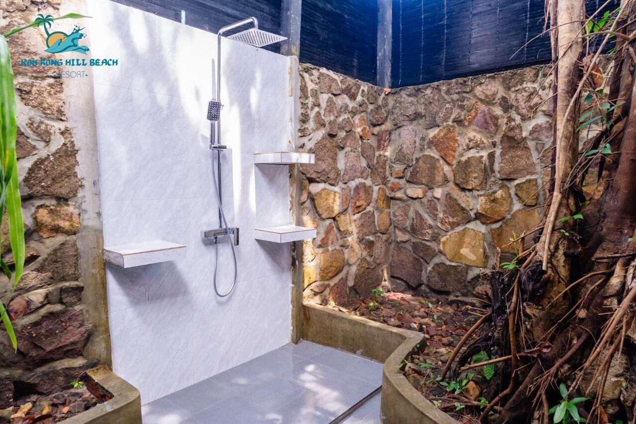 A stone-walled shower enclosure with a built-in shelf and a showerhead.