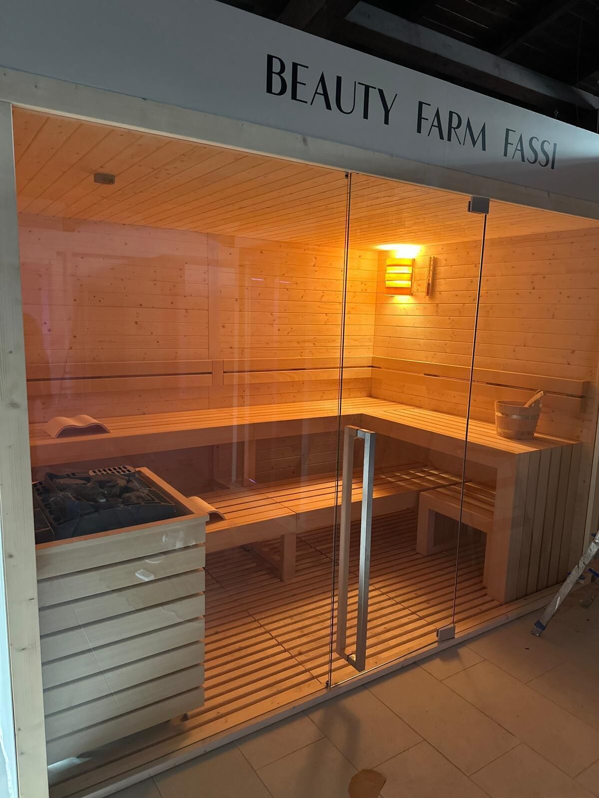 Una sauna con interior de madera, un banco y un calentador visible.