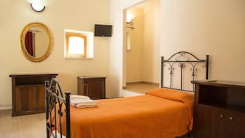 Une chambre à coucher avec un lit, une commode, un miroir, une télévision et une fenêtre.