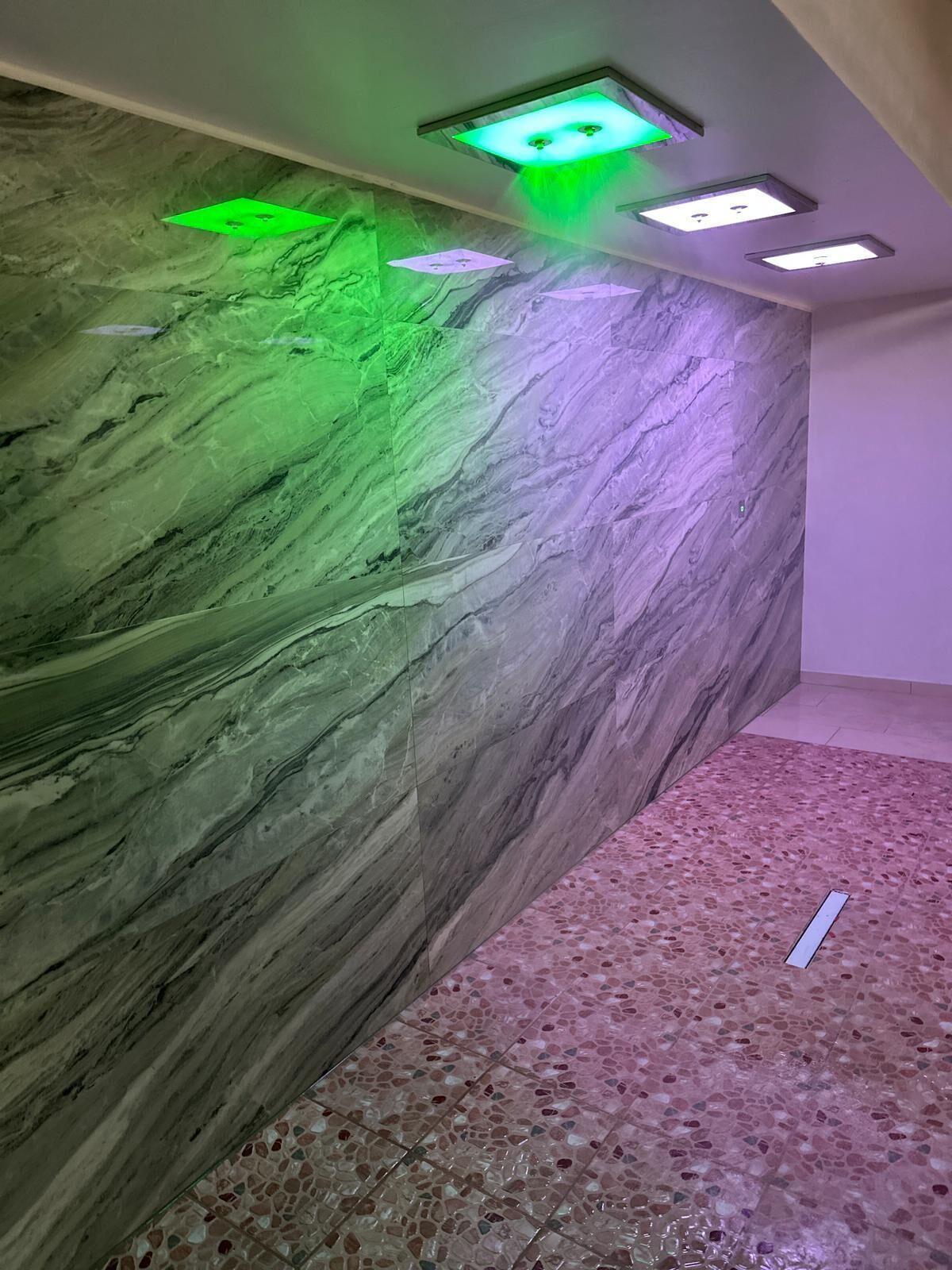 Una habitación con pared de mármol y suelo de terrazo.