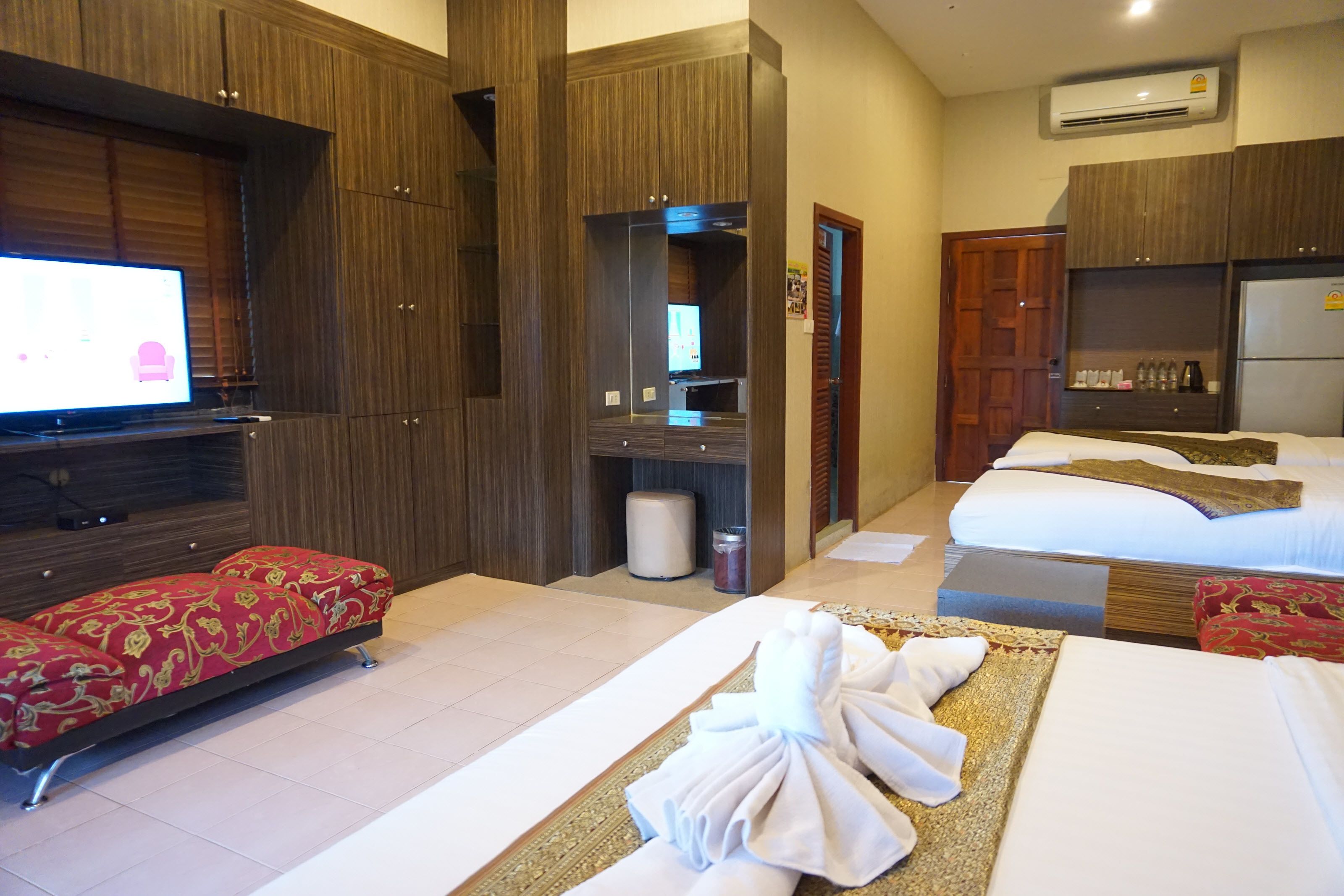 Habitación de hotel con cama, sofá, televisión, minibar y baño.