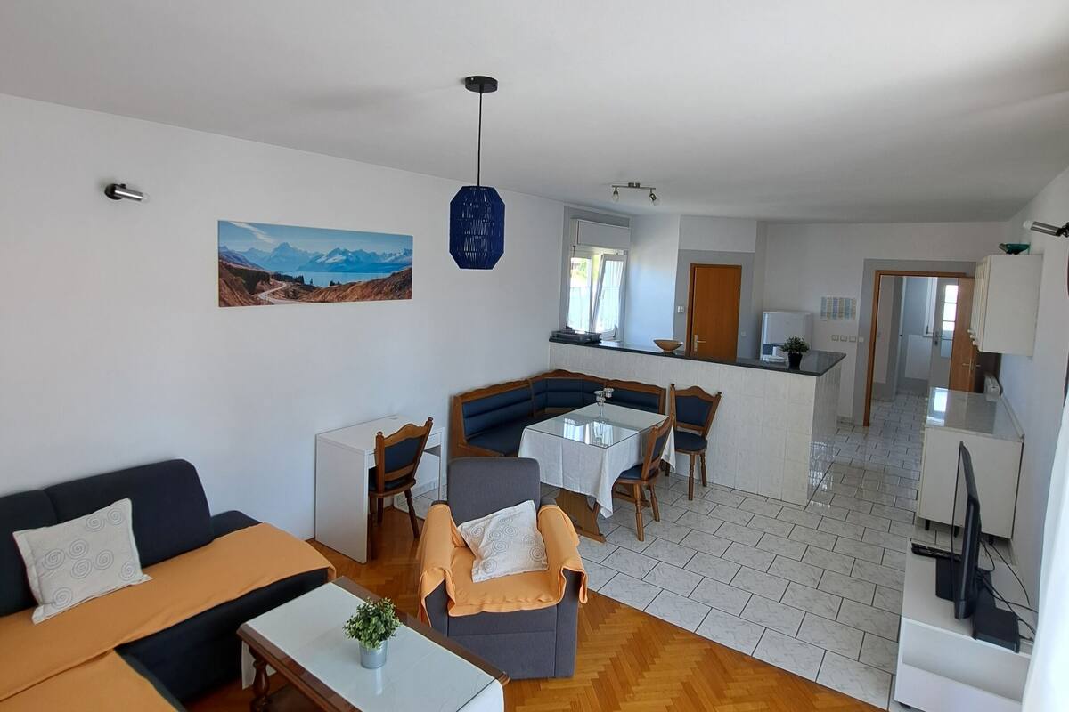 Una sala de estar moderna con un sofá, sillones y un comedor con mesa y sillas.