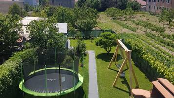 A residential area with a trampoline, a swing set, and a pathway.