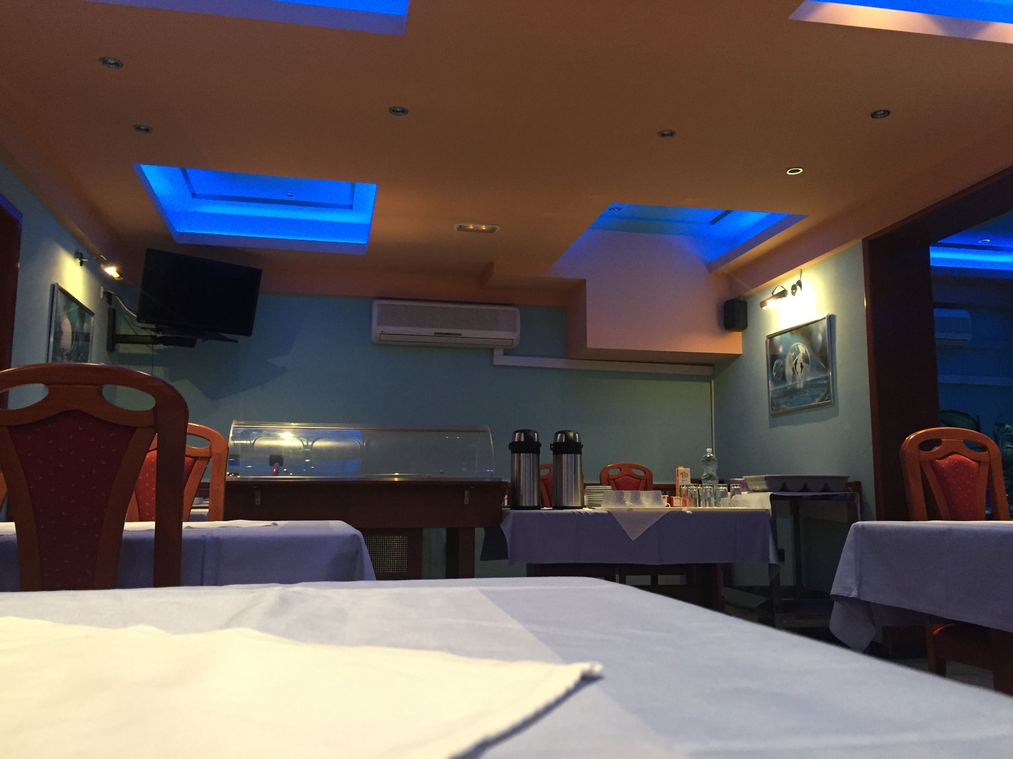 Un interno di ristorante con tavoli, sedie, luci a soffitto e un condizionatore.