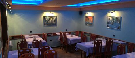 Ein Restaurant mit Tischen und Stühlen, blauen Wänden und Kunstwerken an den Wänden.