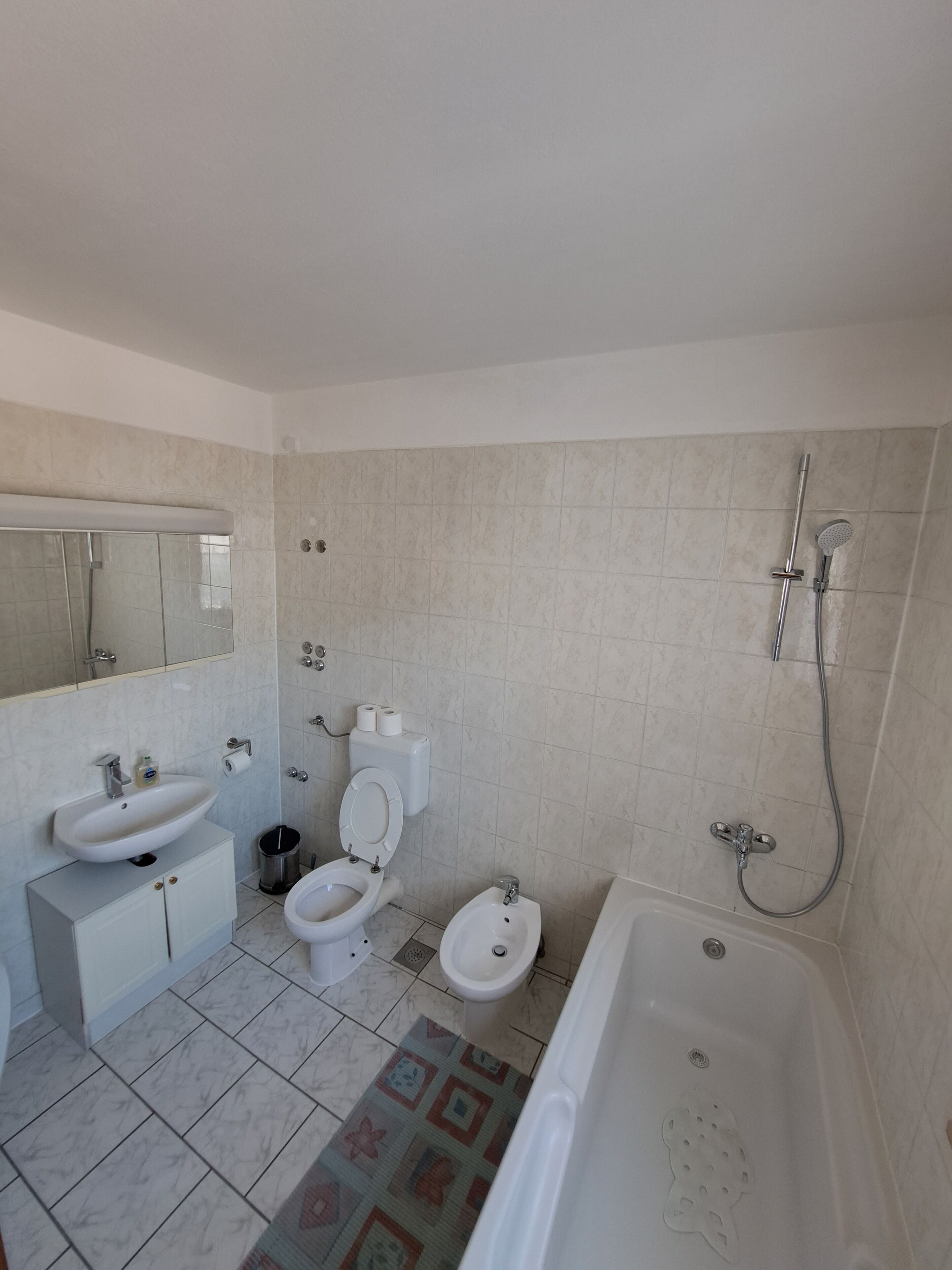 Een badkamer met een wastafel, toilet, bidet en bad.