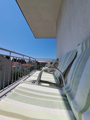 A balcony with a striped sofa and metal railing. - Guesthouse Varnica (Kastela)