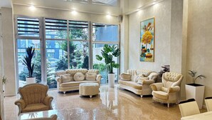 Un salón espacioso con ventanas amplias, un conjunto de sofá color beige, una mesa de centro y una planta en maceta.