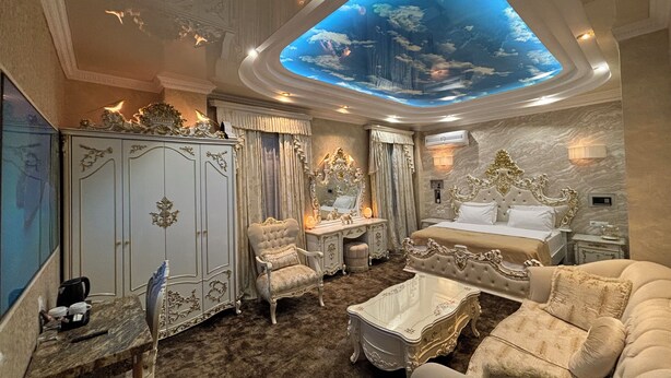 Un dormitorio lujoso con una cama grande, muebles ornamentados y un tragaluz en el techo.