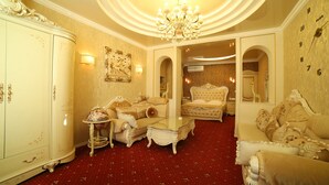 Un salón lujoso con muebles ornamentados, una araña y una alfombra roja.